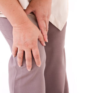 middle aged woman suffering from knee pain, joint injury or arthritis, hand holding knee